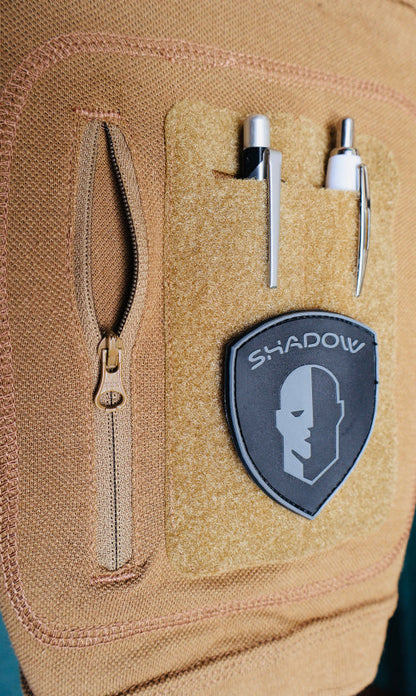 1771 Close up Pocket pic Tan /Coyote with a 'Shadow' logo patch and tools on a green background