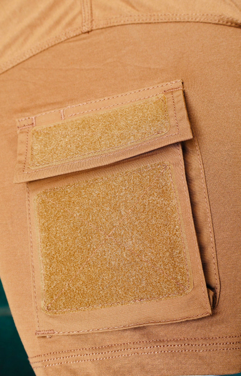 Close-up of a tan T-Shirt with two patches on a green background