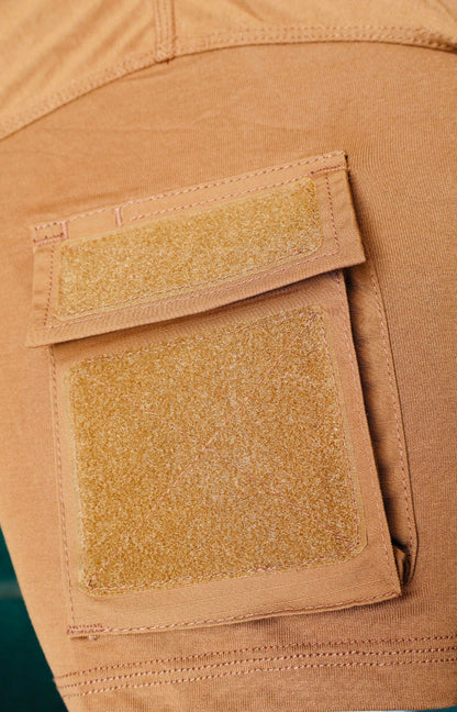 Close-up of a tan T-Shirt with two patches on a green background