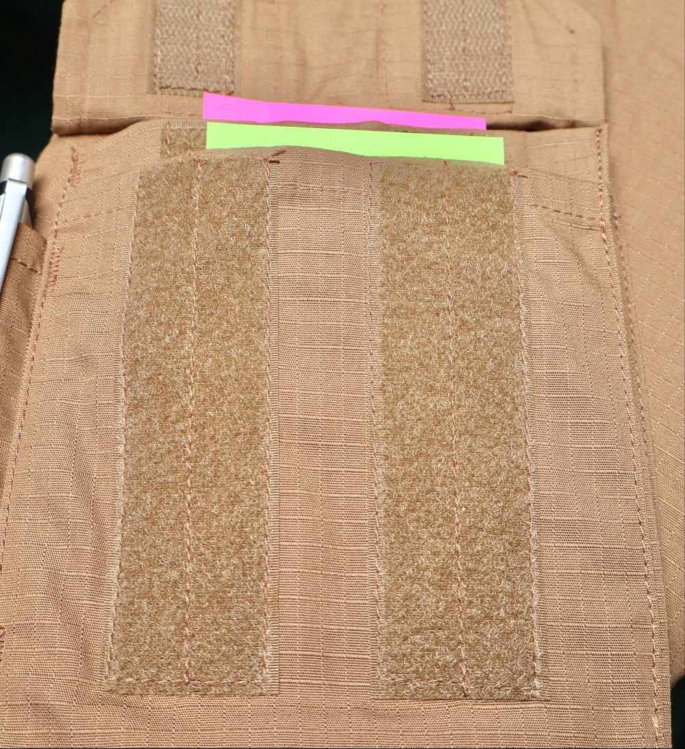 Close-up of a brown tactical vest with multi pocket and fabric patches and a pink and green strip.