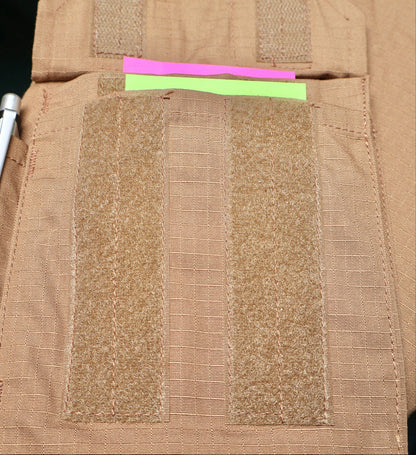 Close-up of a brown tactical vest with multi pocket and fabric patches and a pink and green strip.