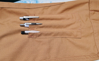 Three pens in a pocket of brown pants with a light-colored background